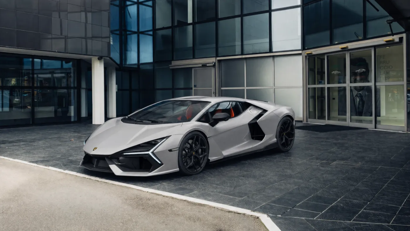 Silver sports car in front of a glass office building